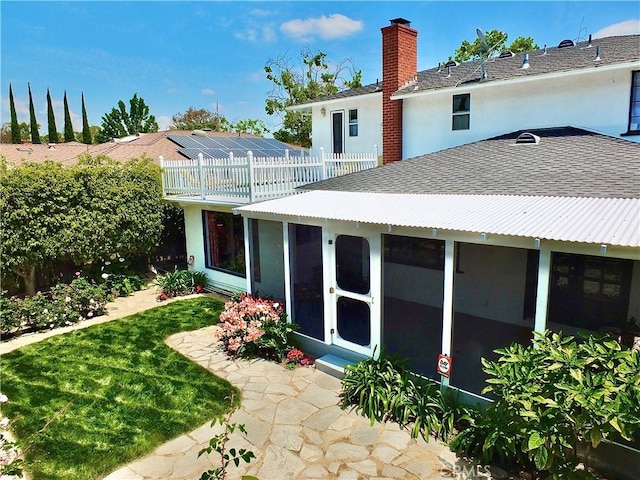 back of property with roof with shingles, fence, a chimney, and a sunroom