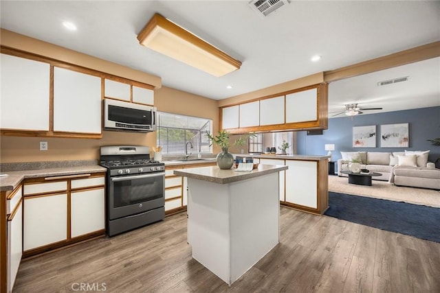 3881 Valle Vista Dr, Chino Hills, CA 91709 - kitchen featuring stainless steel range with gas cooktop, a sink, white cabinets, wood finished floors, and a kitchen island