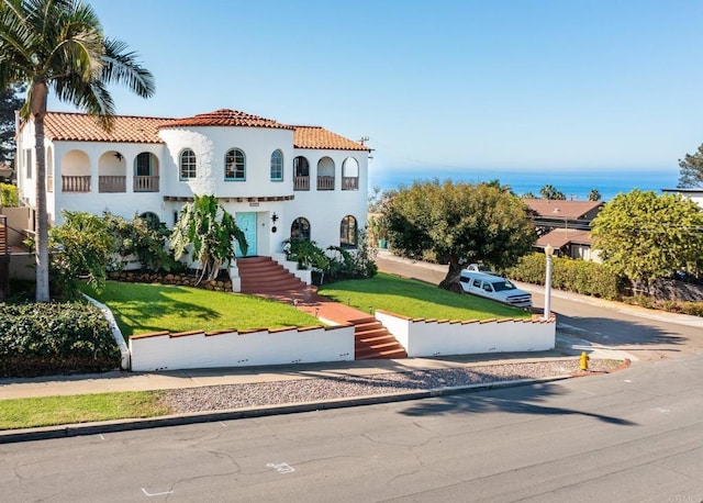 mediterranean / spanish house featuring stucco siding, a front lawn, and a tile roof