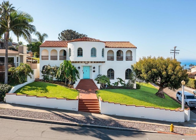 mediterranean / spanish-style house with stucco siding, a front lawn, and a tile roof