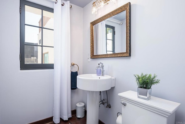 bathroom with toilet, baseboards, and a sink