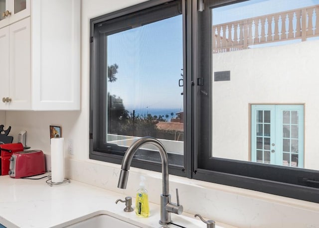 details with glass insert cabinets, light stone counters, and white cabinets