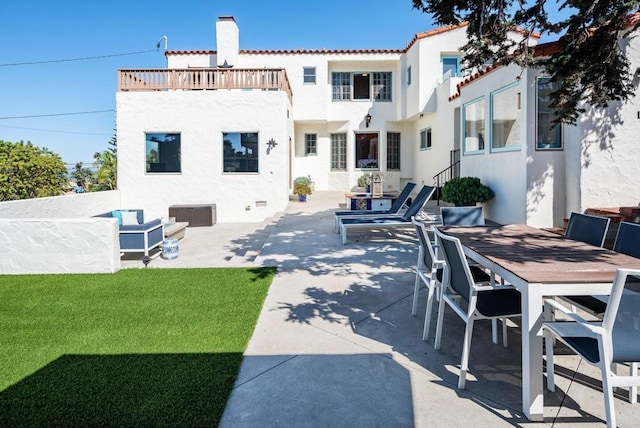 back of house featuring a chimney, outdoor dining space, a patio area, and stucco siding