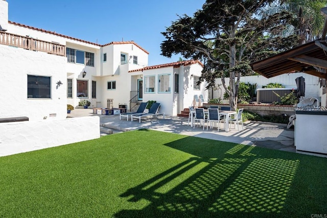 rear view of house with a tile roof, fence, a yard, a patio, and stucco siding