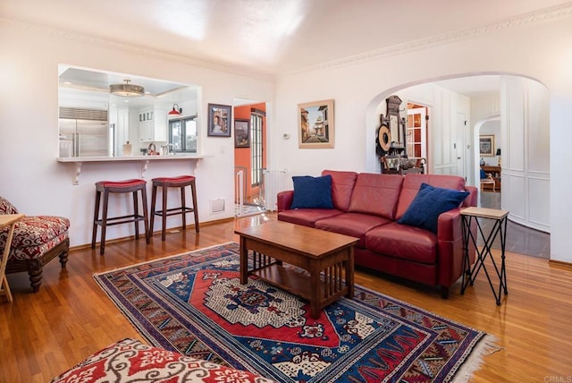 living area featuring visible vents, arched walkways, lofted ceiling, and wood finished floors