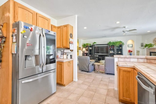 kitchen with a ceiling fan, tile countertops, recessed lighting, open floor plan, and stainless steel appliances
