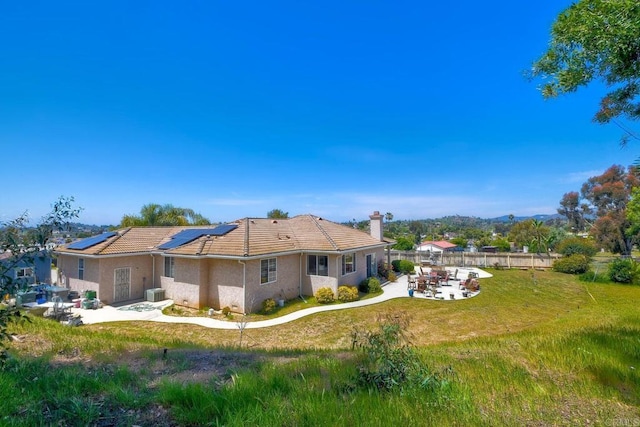 back of house featuring solar panels, a tile roof, central air condition unit, a yard, and a patio