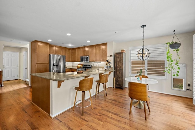 1752 Cottonwood Dr, Vista, CA 92081 - kitchen with stainless steel appliances, stone counters, a sink, a kitchen bar, and light wood-type flooring