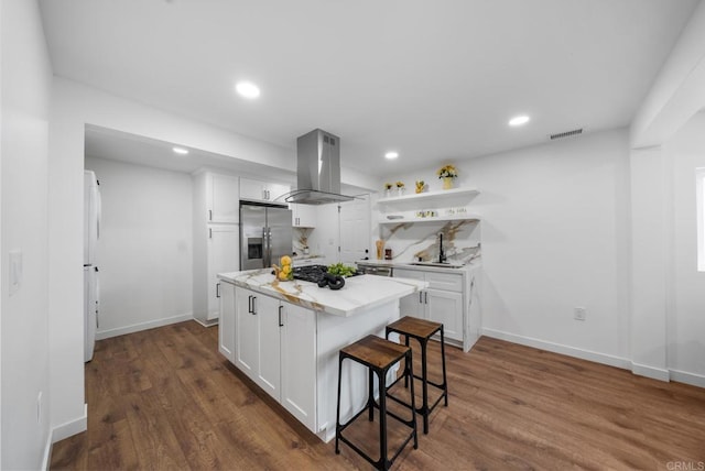 kitchen with white cabinets, visible vents, island range hood, and stainless steel fridge with ice dispenser