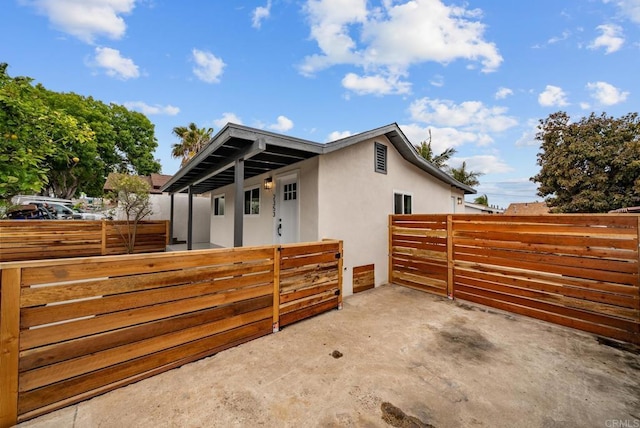 view of side of home with fence, a patio, and stucco siding