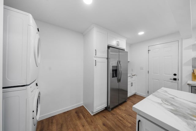 kitchen featuring stainless steel fridge, stacked washer and dryer, dark wood finished floors, and white cabinetry