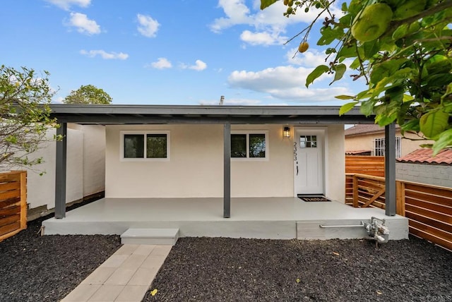 view of front of home featuring fence, stucco siding, and a patio area