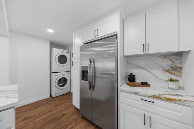 kitchen featuring stainless steel fridge with ice dispenser, stacked washer / drying machine, white cabinetry, and dark wood-type flooring