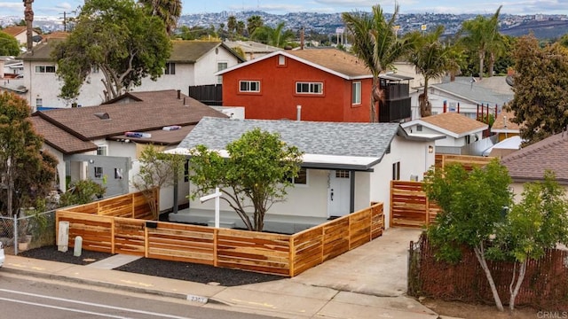 view of front facade featuring a shingled roof, a residential view, fence private yard, and stucco siding