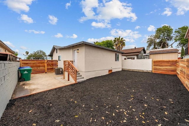 rear view of property featuring stucco siding, a fenced backyard, a patio area, and central AC