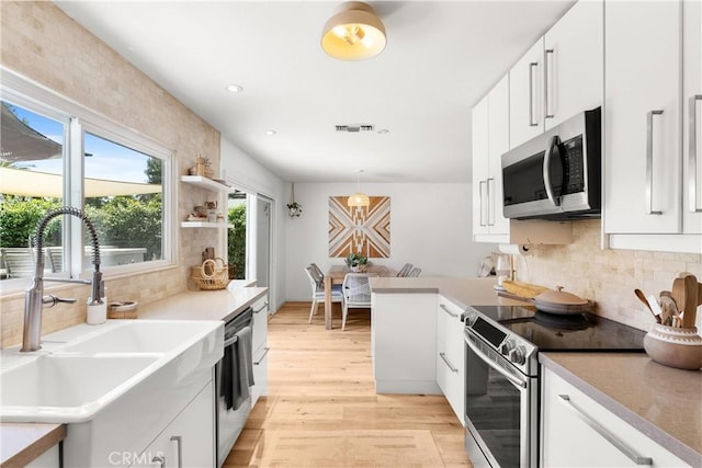 22352 Torino, Laguna Hills, CA 92653 - kitchen featuring stainless steel appliances, a sink, light wood finished floors, backsplash, and white cabinets