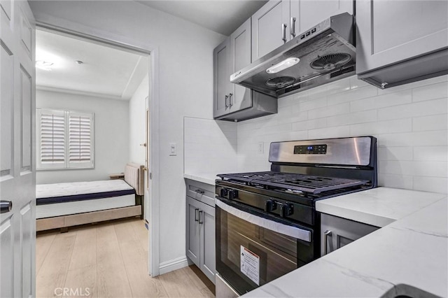 1302 S Gladys Ave, San Gabriel, CA 91776 - kitchen featuring stainless steel range with gas stovetop, under cabinet range hood, gray cabinets, tasteful backsplash, and light stone counters