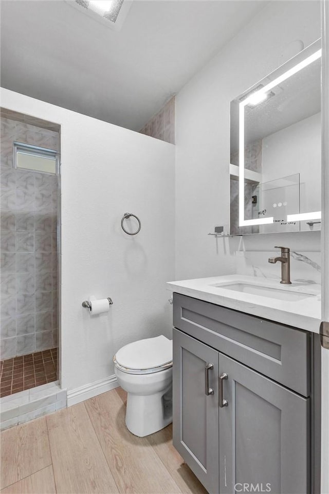 1302 S Gladys Ave, San Gabriel, CA 91776 - bathroom featuring a tile shower, toilet, vanity, and wood finished floors