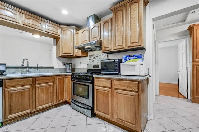 1302 S Gladys Ave, San Gabriel, CA 91776 - kitchen featuring stainless steel range with gas stovetop, under cabinet range hood, white microwave, a sink, and light tile patterned floors