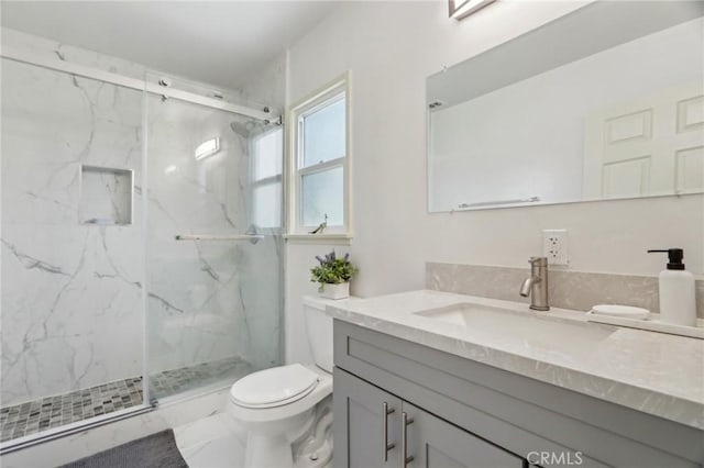 bathroom featuring a marble finish shower, vanity, and toilet