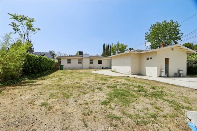 rear view of house with a lawn, a patio, and stucco siding
