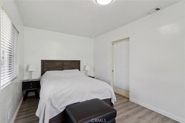 bedroom with baseboards, wood finished floors, and visible vents