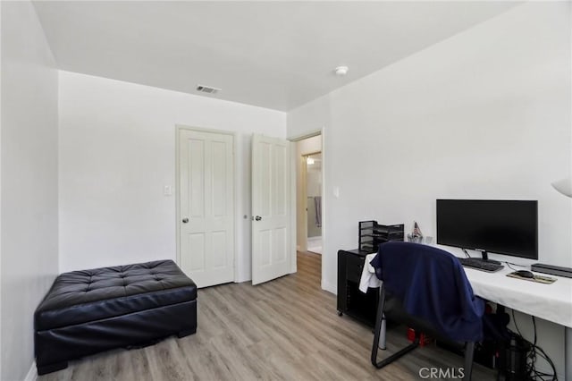 office area with baseboards, visible vents, and light wood-style flooring
