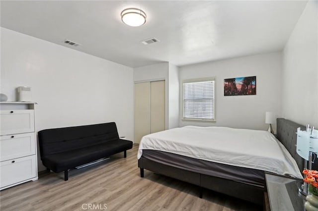 bedroom featuring a closet, light wood-style flooring, and visible vents