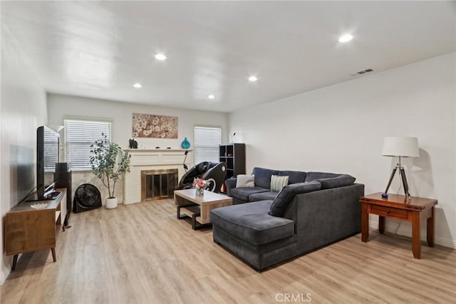 living area with a fireplace, recessed lighting, visible vents, and light wood-type flooring