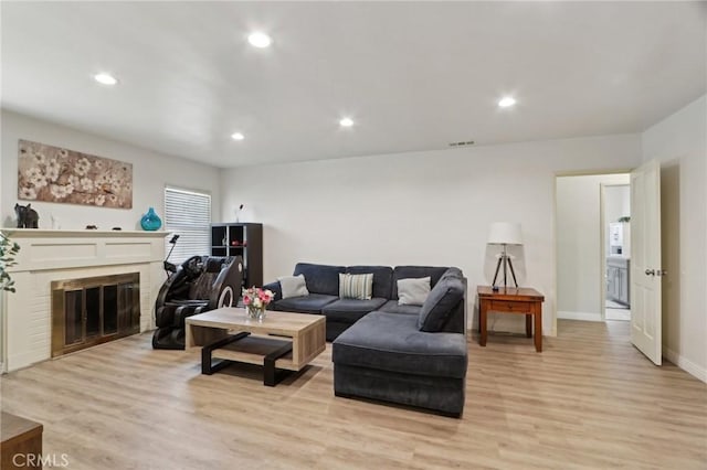 living room featuring visible vents, a fireplace, light wood-style floors, baseboards, and recessed lighting