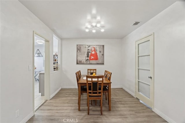dining room with light wood-style floors, baseboards, and visible vents
