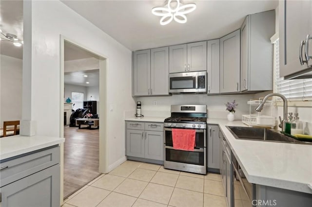 kitchen with a sink, gray cabinets, and stainless steel appliances