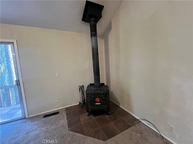 interior details featuring visible vents, baseboards, carpet, and a wood stove