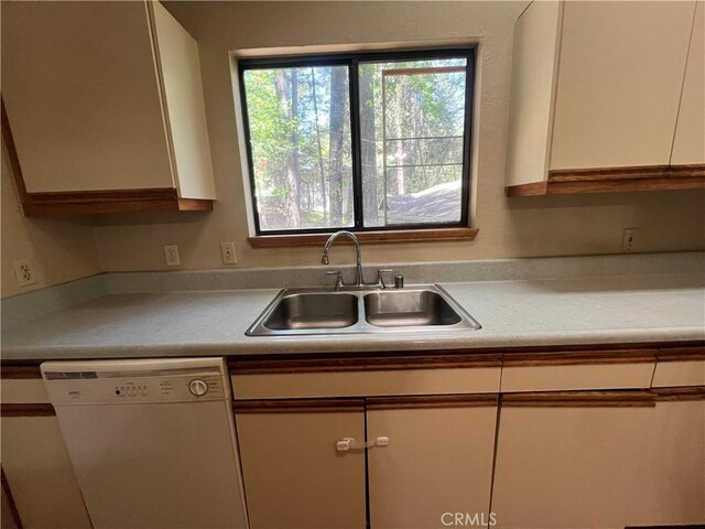 kitchen featuring white dishwasher, a sink, white cabinetry, and light countertops