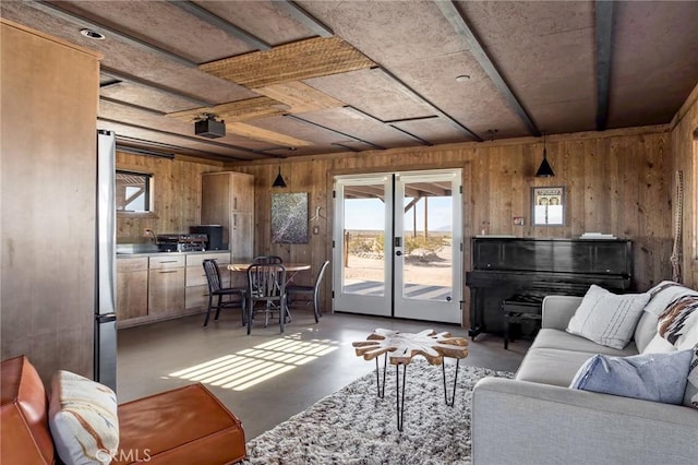 living area with concrete flooring, french doors, and wood walls