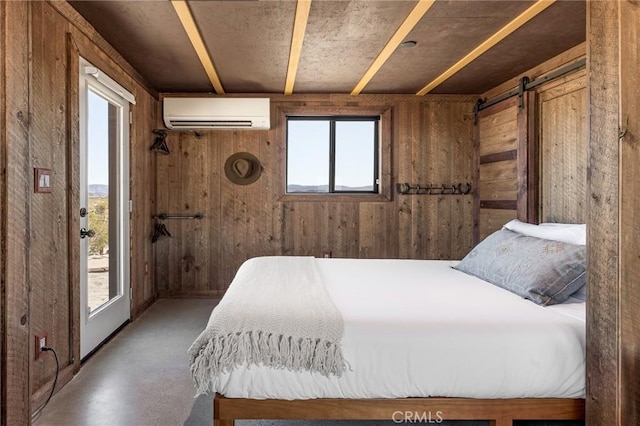 bedroom with a wall unit AC, wood walls, and a barn door