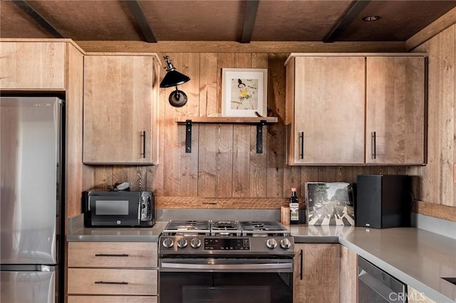 kitchen with light countertops, appliances with stainless steel finishes, wood walls, and beam ceiling