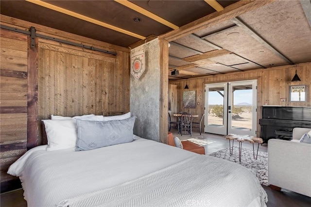 bedroom featuring wooden walls, a barn door, and access to exterior