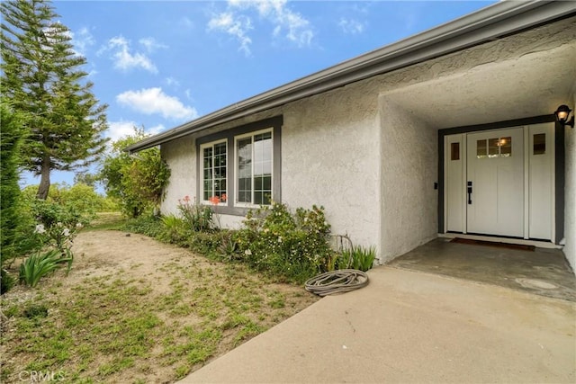 entrance to property featuring a patio and stucco siding
