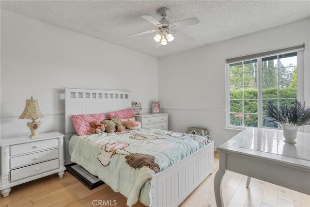 bedroom featuring light wood-style floors, a textured ceiling, and ceiling fan