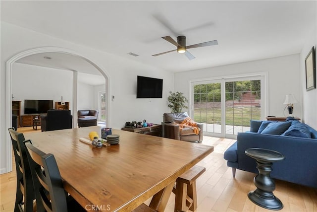 dining area featuring arched walkways, ceiling fan, visible vents, and light wood-style floors