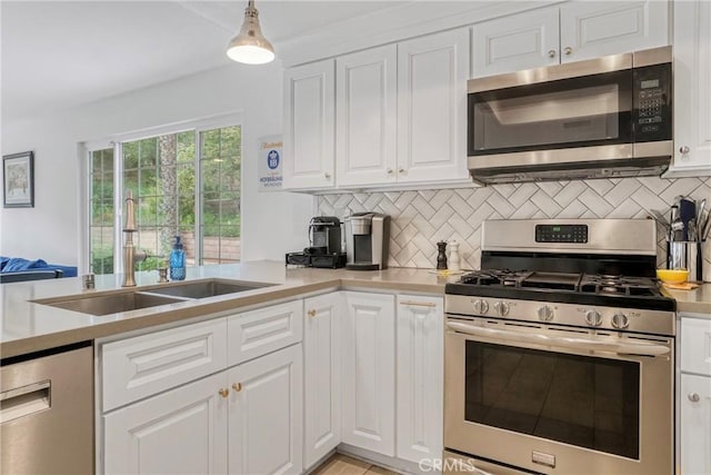 kitchen with a sink, light countertops, stainless steel appliances, white cabinetry, and backsplash