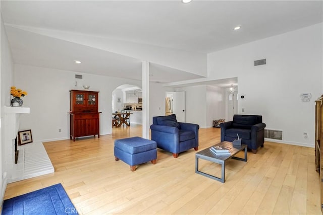 living room featuring visible vents, arched walkways, recessed lighting, and light wood-type flooring