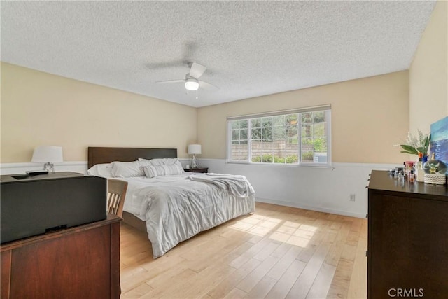 bedroom with light wood-style floors, a textured ceiling, and ceiling fan