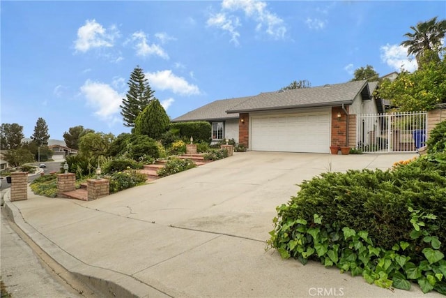 view of front facade with a garage, fence, concrete driveway, and brick siding