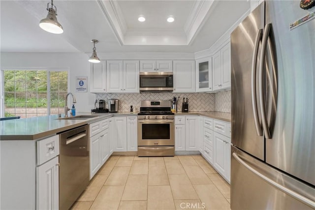 kitchen featuring appliances with stainless steel finishes, tasteful backsplash, a sink, a peninsula, and a tray ceiling