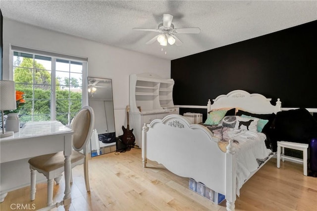 bedroom with a textured ceiling, ceiling fan, and light wood-style flooring