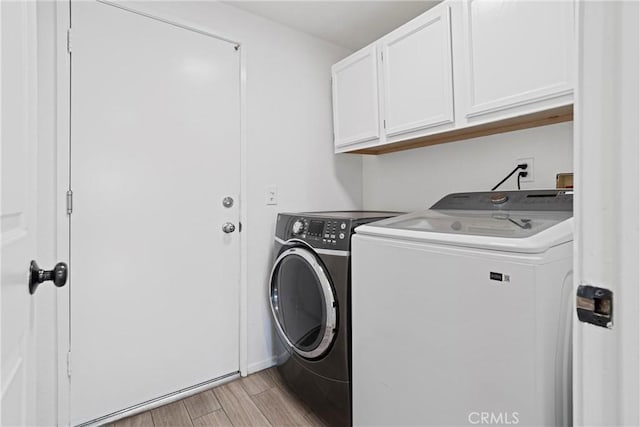 clothes washing area with light wood-style floors, cabinet space, and washing machine and clothes dryer