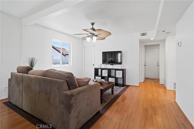 living room featuring baseboards, ceiling fan, visible vents, and light wood-style flooring