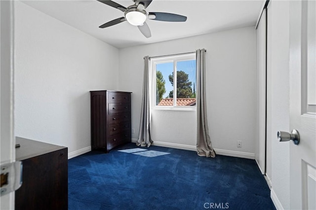unfurnished bedroom with baseboards, ceiling fan, and dark carpet
